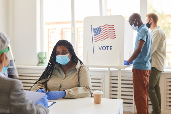 Multi-ethnic group of people wearing masks voting at polling station on post-pandemic election day, copy space