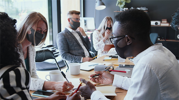 People wearing masks around a conference room table