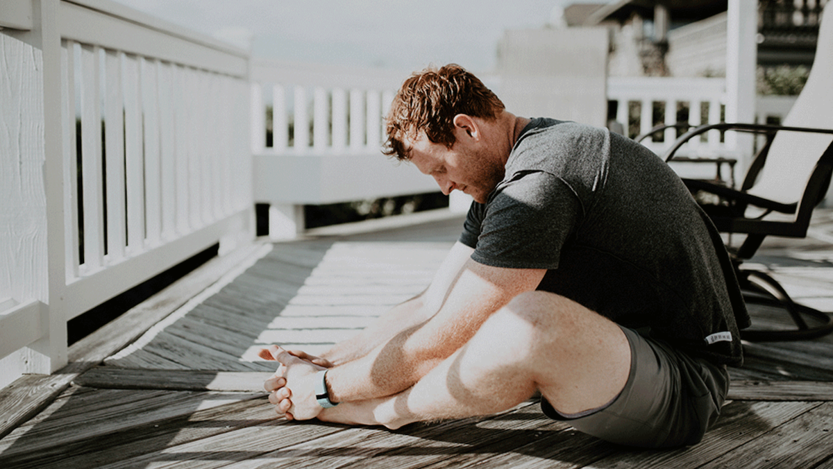 man mindfully stretching on a deck